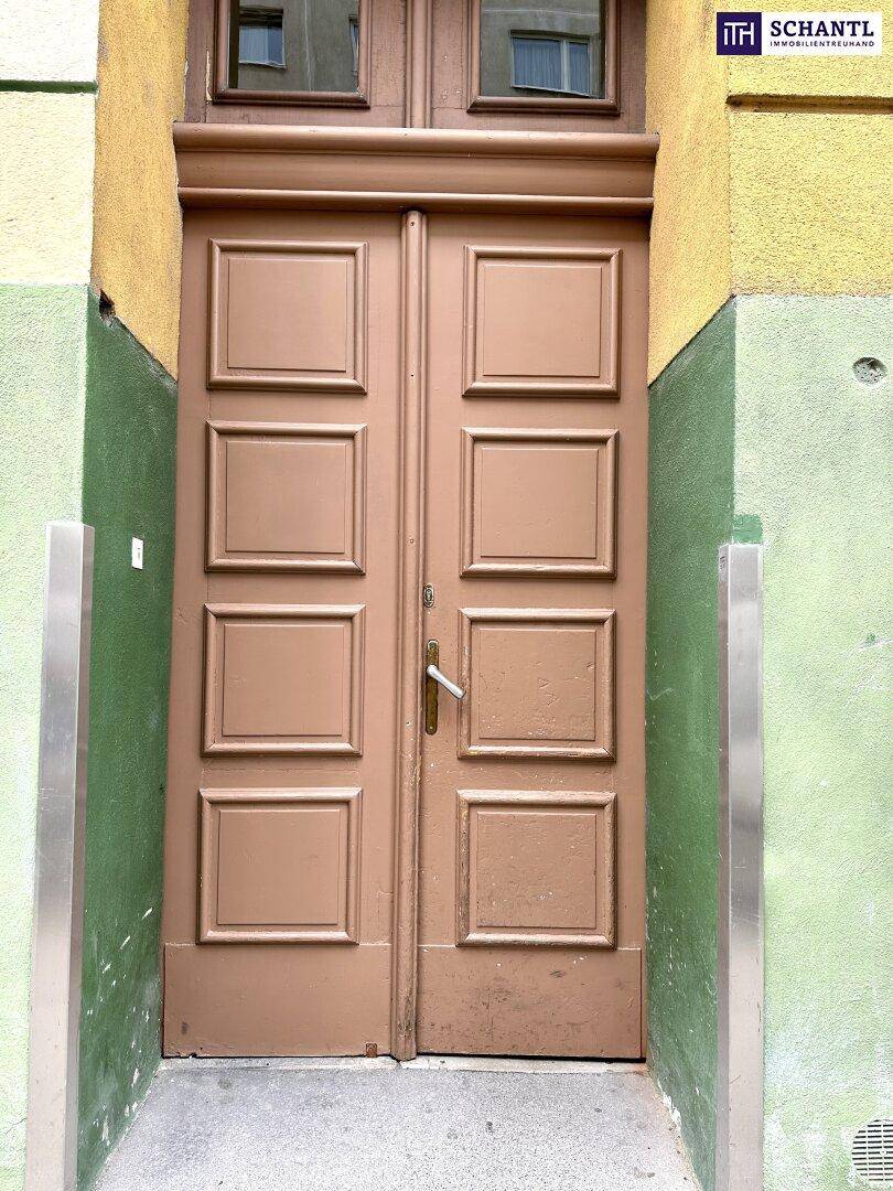 Braune, getäfelte Eingangstür in einer farbigen Fassade mit grünen und gelben Akzenten.