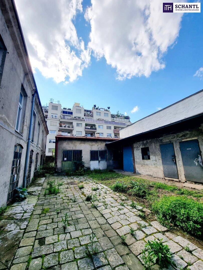 Innenhof mit alten Gebäuden, gepflastertem Boden und Blick auf moderne Dächer.