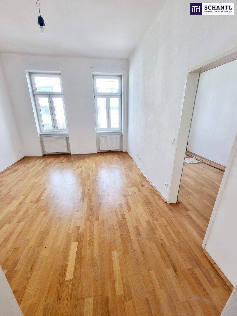 Helles Wohnzimmer mit Eichenparkettboden und zwei großen Fenstern.