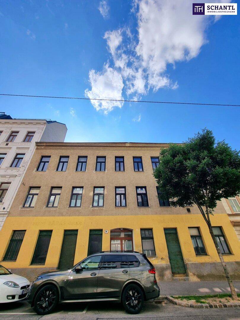Historische Gebäudefassade mit gelber und grauer Farbgebung an einer Stadtstraße.
