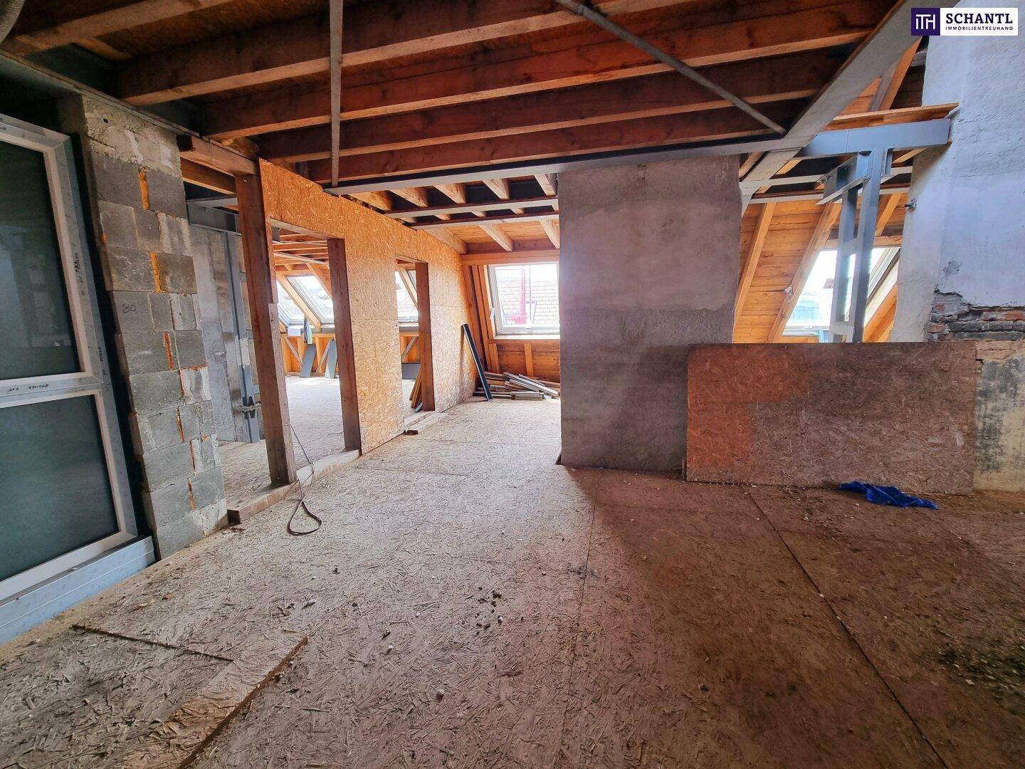 Geräumiger, unfertiger Dachbodenbereich mit Holzbalken und OSB-Platten, ideal für den Ausbau.