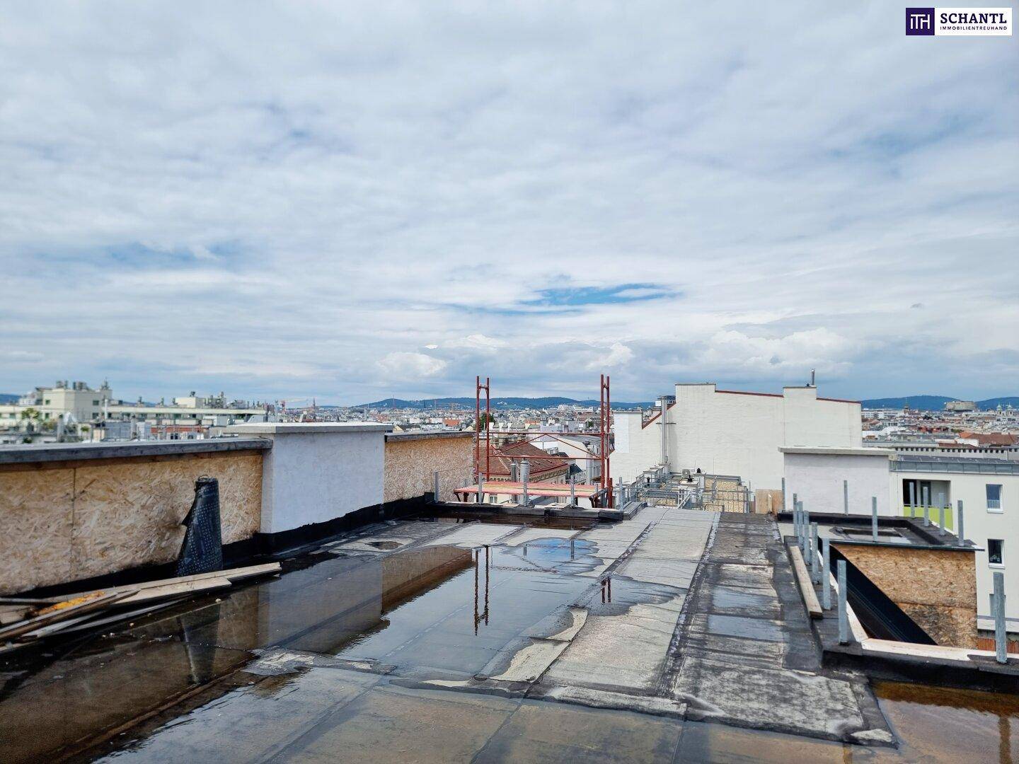 Weitläufiger Blick über die Stadt von einem Flachdach mit Bauarbeiten im Vordergrund.