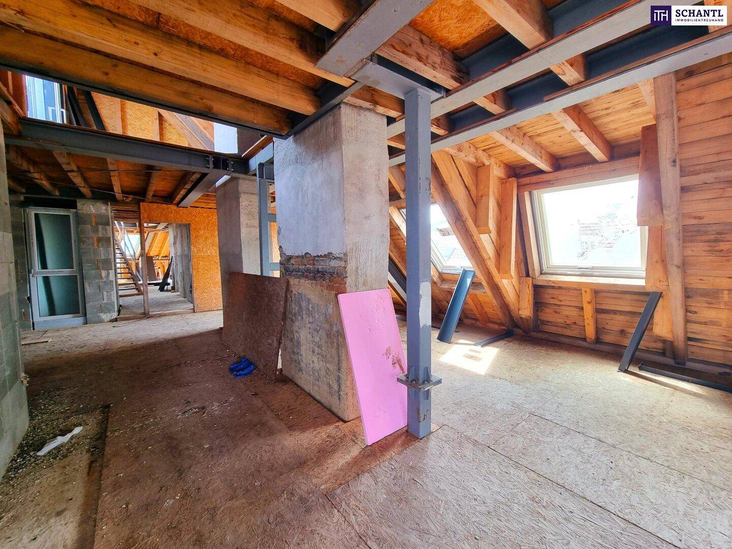 Geräumiger Dachboden im Rohbau mit Holzbalken und Dachschrägen, ideal für zukünftige Wohnräume.
