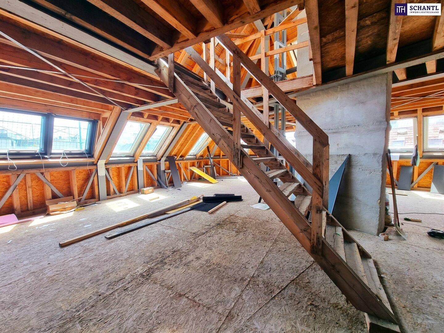 Geräumiger unausgebauter Dachboden mit Holztreppe und vielen Dachfenstern, bereit zum Ausbau.