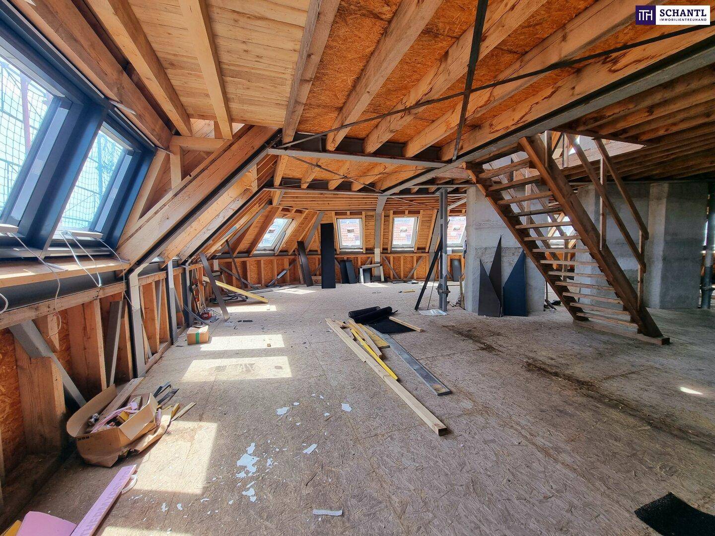 Großer unausgebauter Dachboden mit Holztreppe, Dachfenstern und sichtbaren Holzbalken.