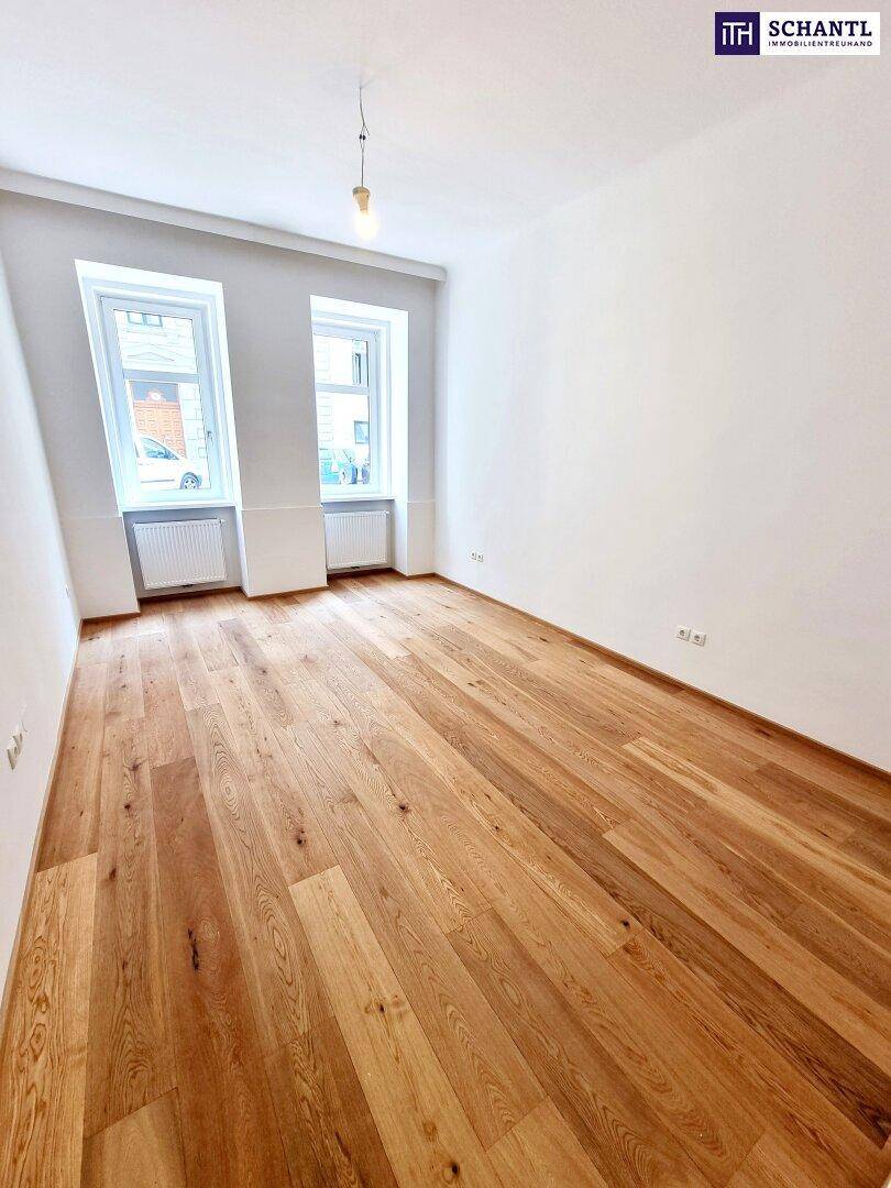 Geräumiger, heller Raum mit Holzparkett und zwei Fenstern, ideal für vielfältige Nutzungsmöglichkeiten.