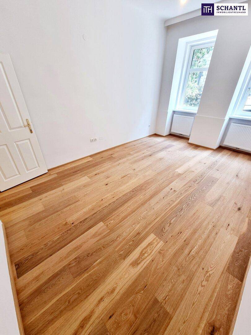 Lichtdurchfluteter Raum mit neuem Holzparkett und zwei Fenstern, bietet vielseitige Gestaltungsmöglichkeiten.