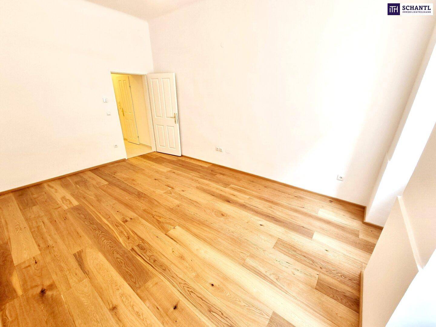 Leerer Raum mit neu verlegtem Holzparkett und weißen Wänden, bereit zur individuellen Gestaltung.