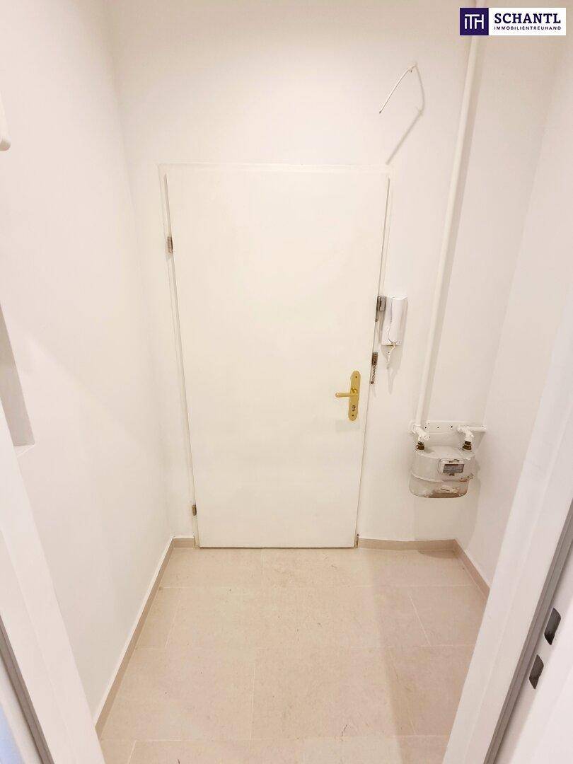 Eingangsbereich mit weißer Wohnungstür und Gegensprechanlage, hell gefliest.