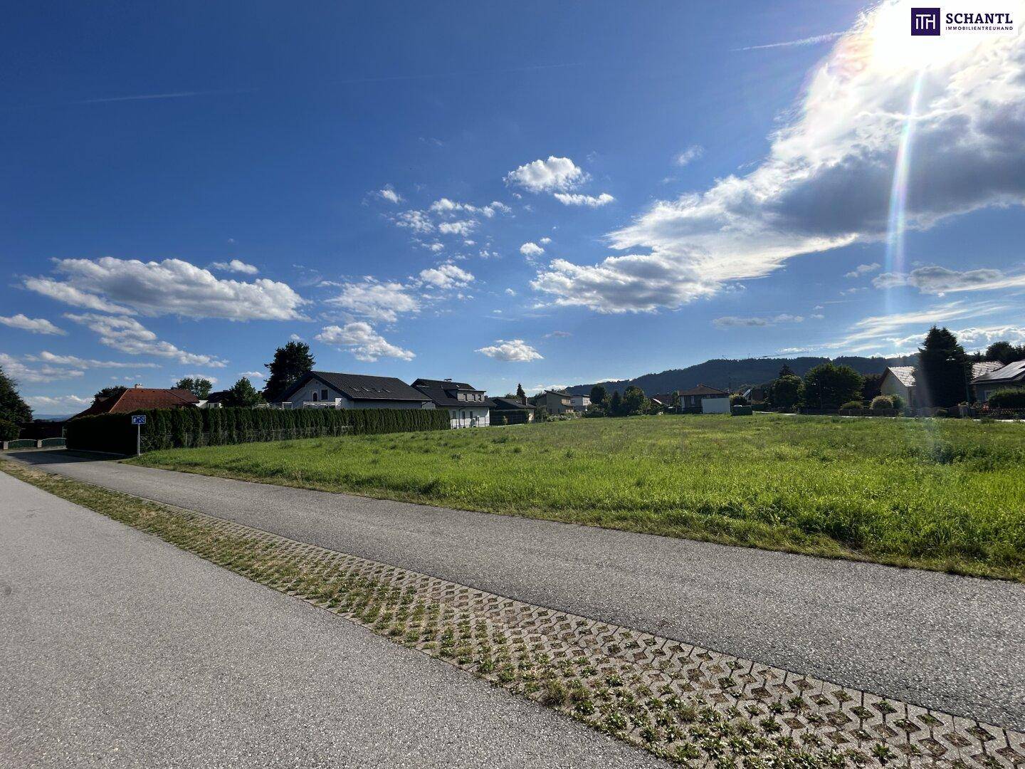 Sonniges, offenes Grundstück mit weitem Blick auf die grüne Landschaft und die entfernten Berge.