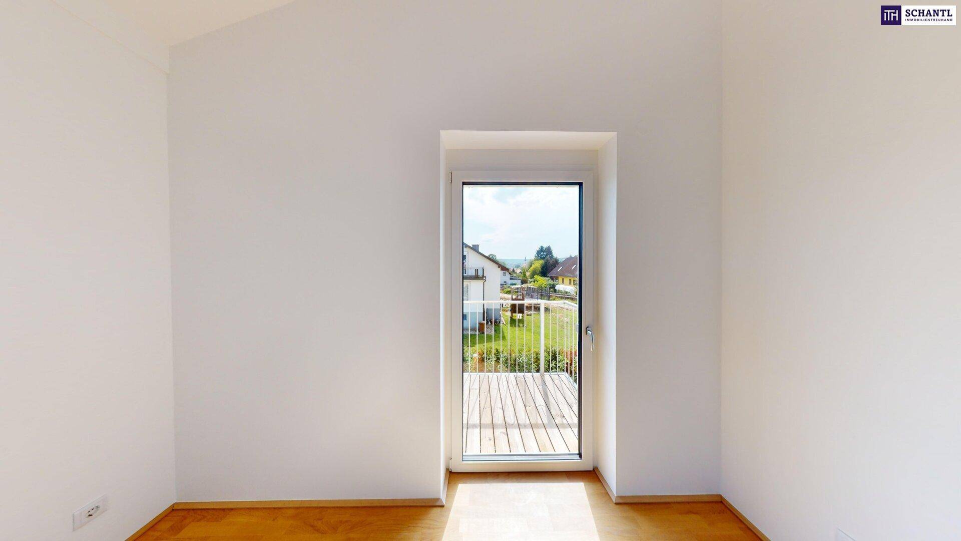 Helles Zimmer mit Parkettboden und großem Fenster, das Zugang zu einem Balkon oder einer Terrasse bietet.