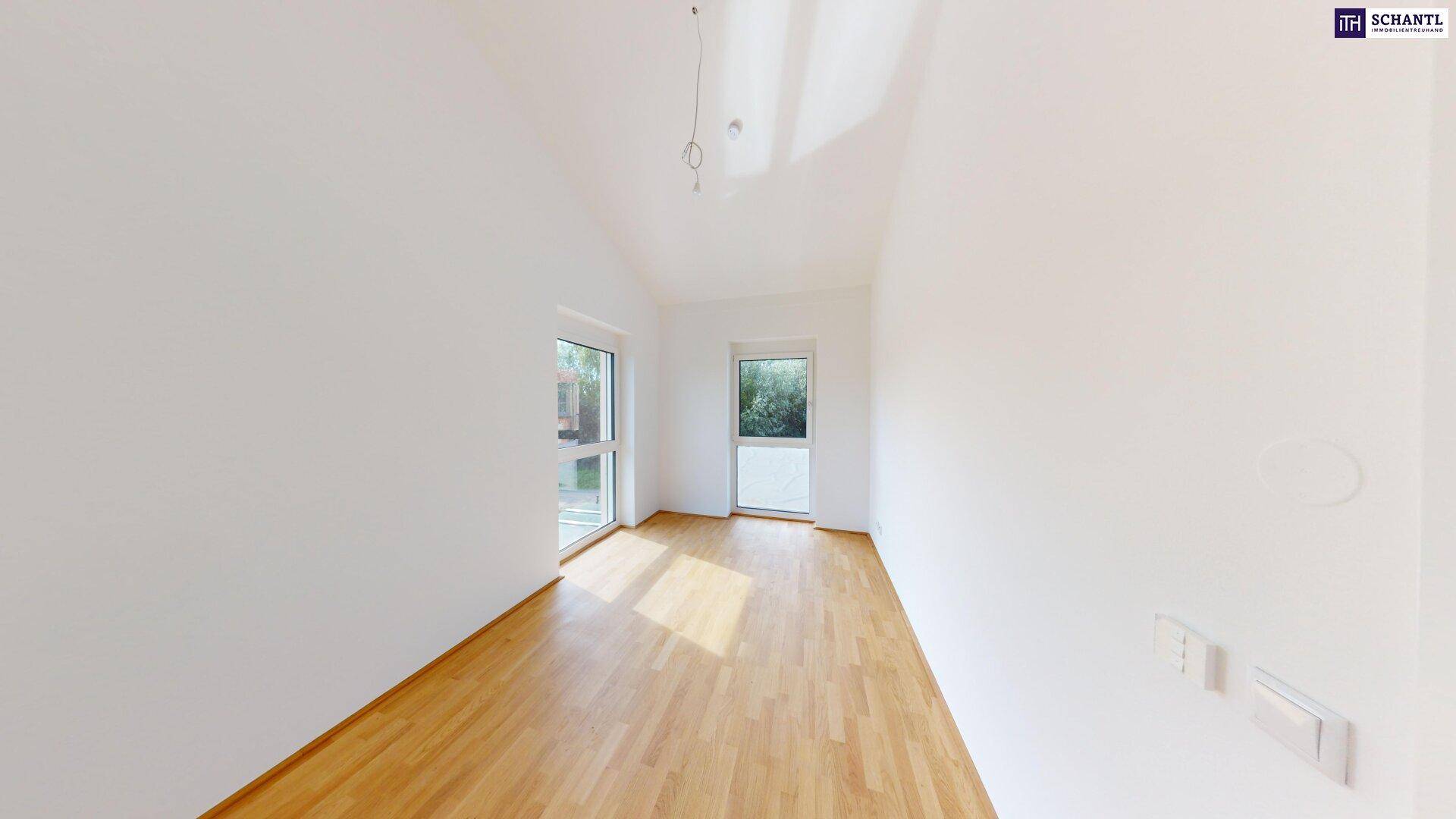 Helles Schlafzimmer mit Parkettboden und großen Fenstern, die viel Tageslicht hereinlassen.
