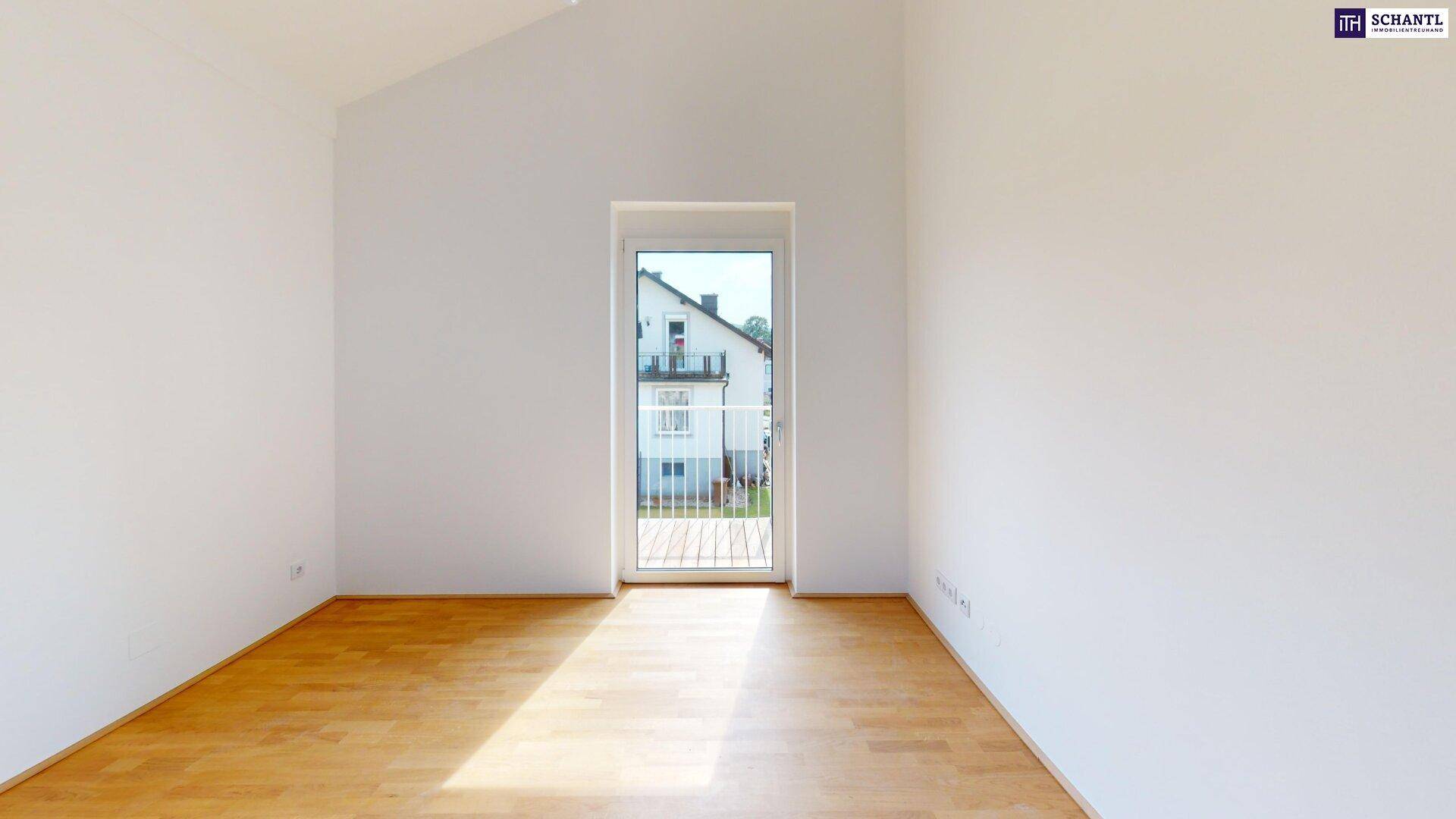 Helles Zimmer mit Parkettboden und großem Fenster, das Zugang zu einem kleinen Balkon oder einer Terrasse bietet.