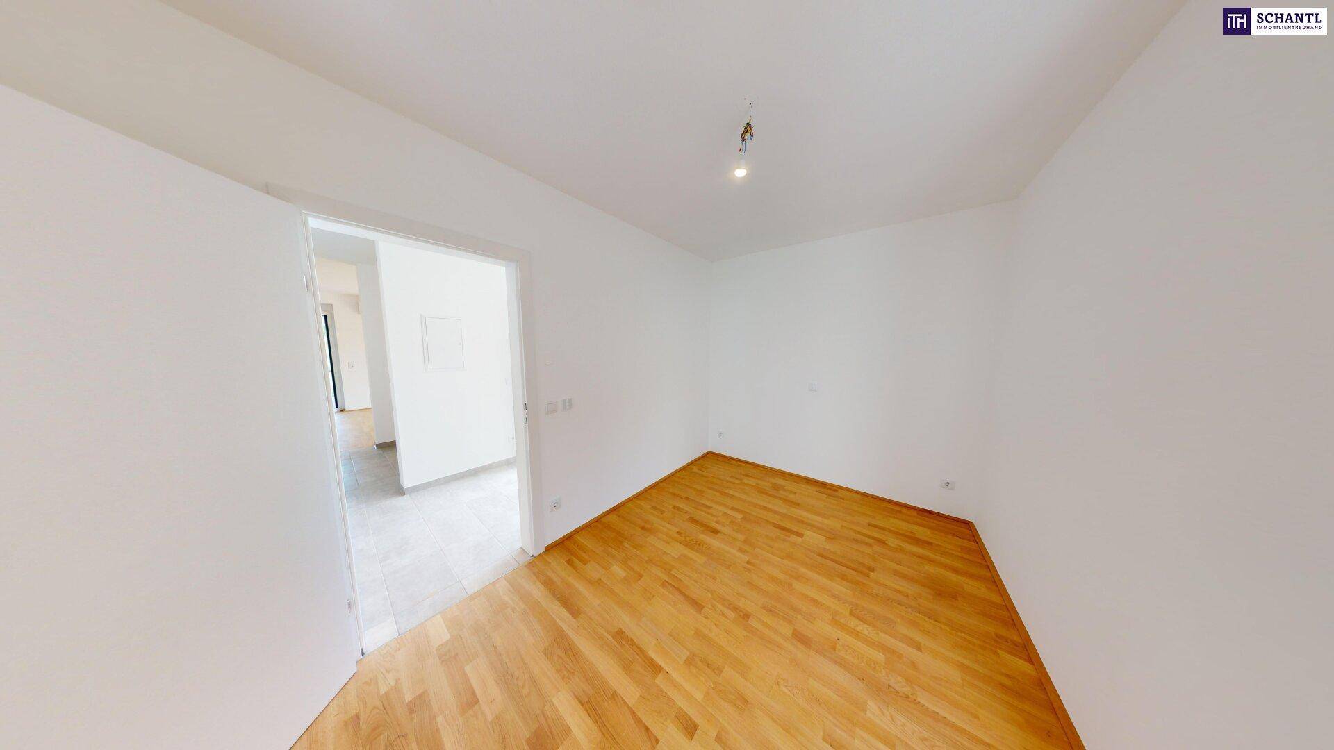 Helles Schlafzimmer mit Holzboden und Zugang zu einem angrenzenden Bereich.
