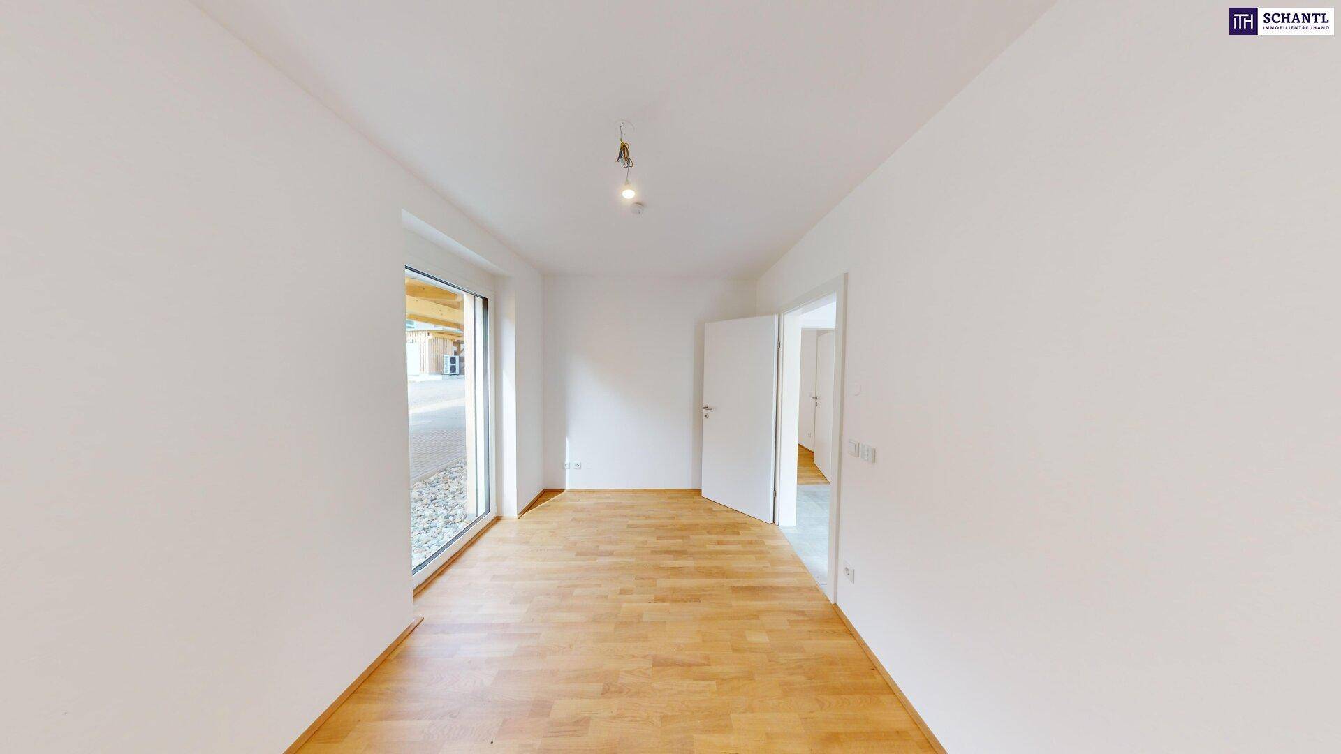 Geräumiges Zimmer mit Holzboden und großer Fensterfront zum Außenbereich.