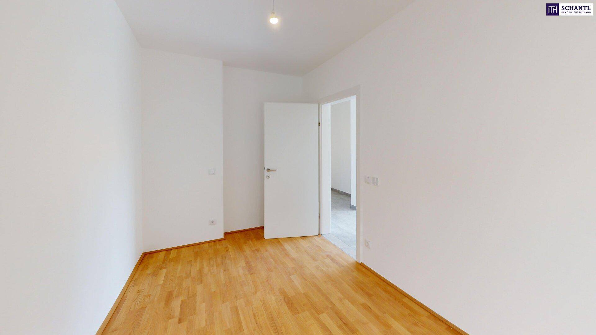 Helles Schlafzimmer mit Holzboden und Zugang zu einem weiteren Raum.