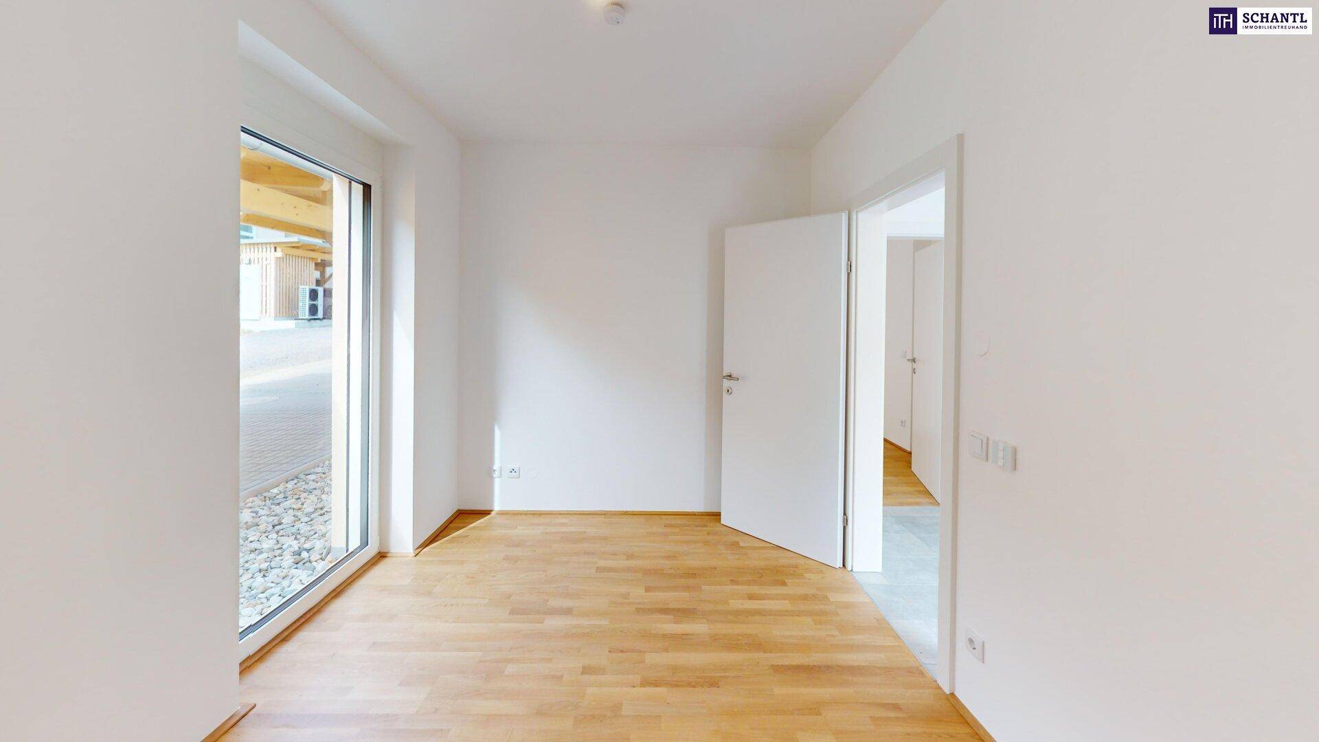 Freundliches Zimmer mit Holzboden und großem Fenster zum Außenbereich.
