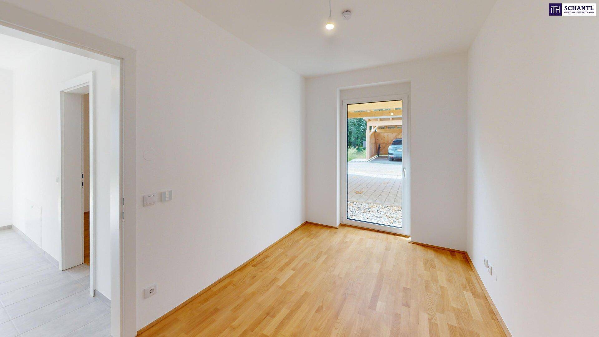 Helles Zimmer mit Holzboden und Blick auf den Carport durch die Tür.