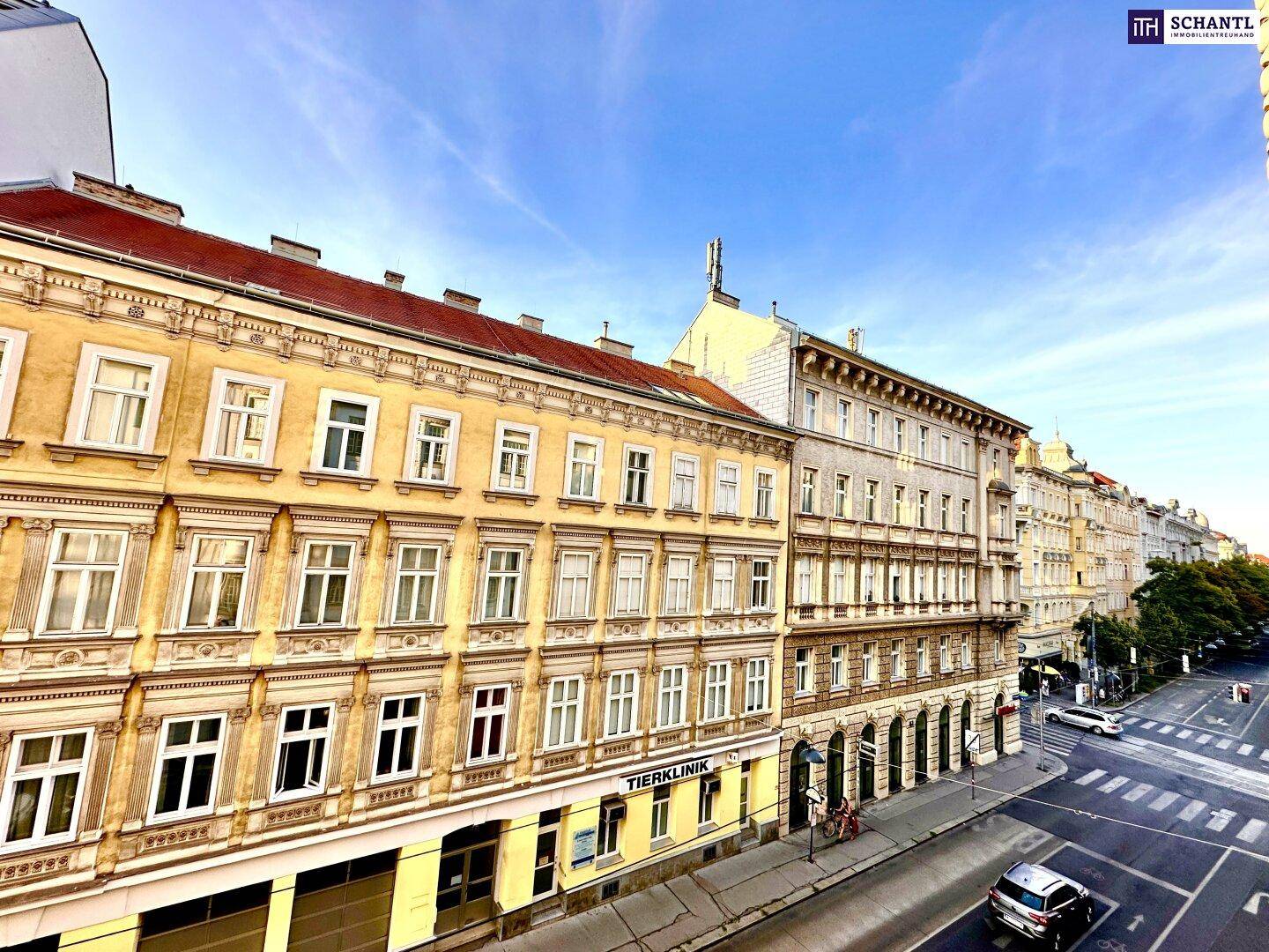 Blick auf eine belebte Stadtstraße mit historischen Gebäuden und parkenden Autos.