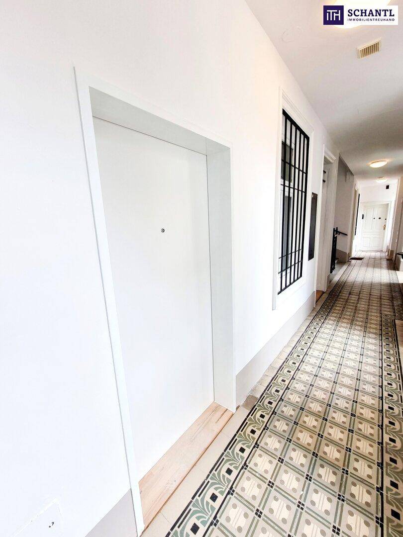 Heller Flur in einem Altbau mit charakteristischen gemusterten Fliesen und einer modernen weißen Wohnungstür.