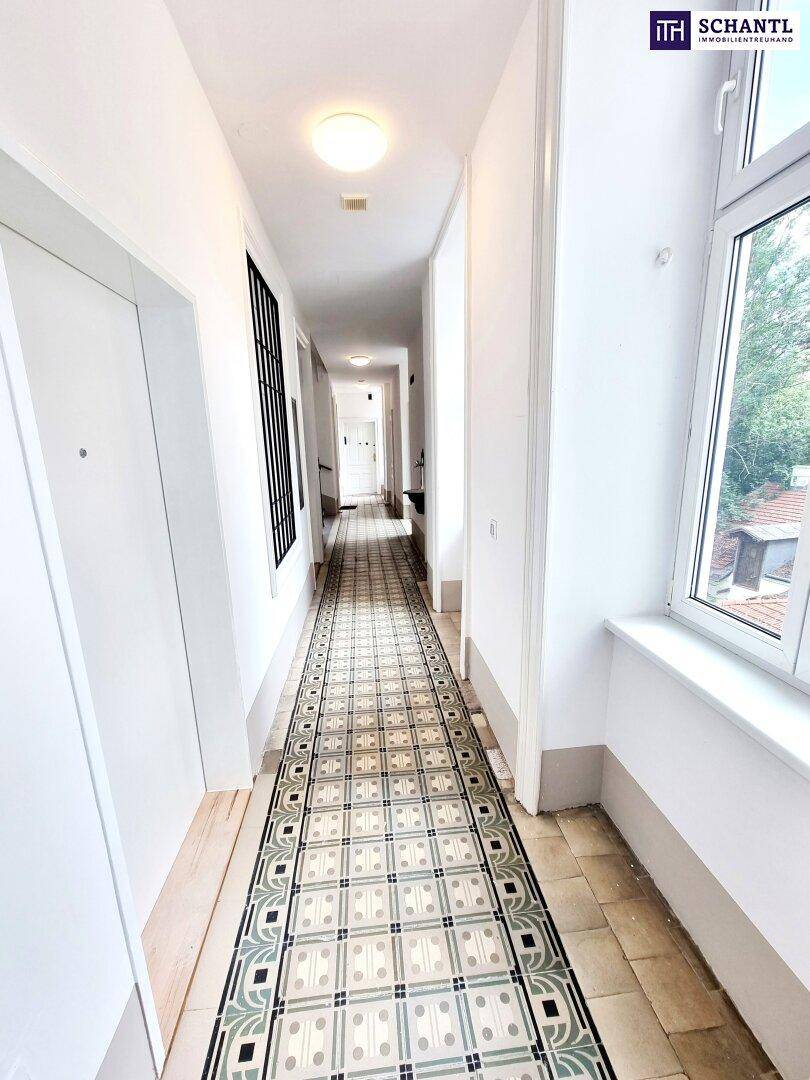 Langer, heller Flur mit auffälligem Fliesenboden und einem großen Fenster, das viel Licht spendet.