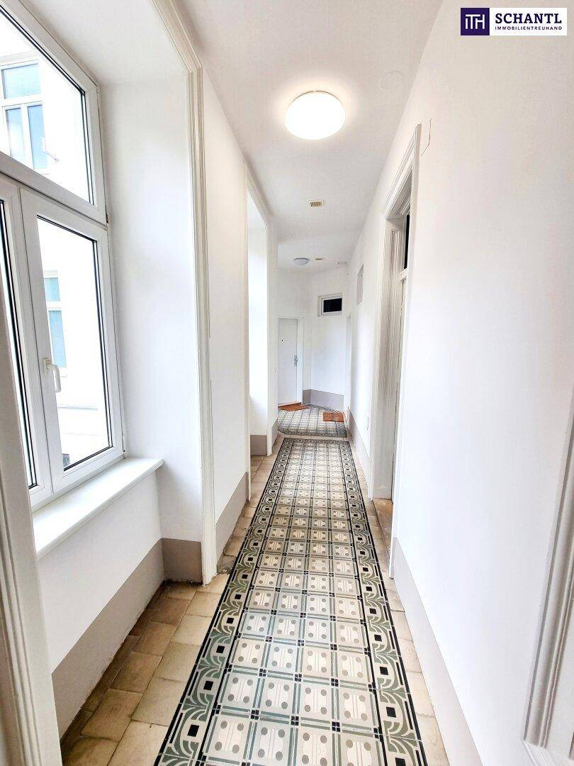 Heller Hausflur mit großen Fenstern und historischem Fliesenboden, bietet viel Tageslicht.