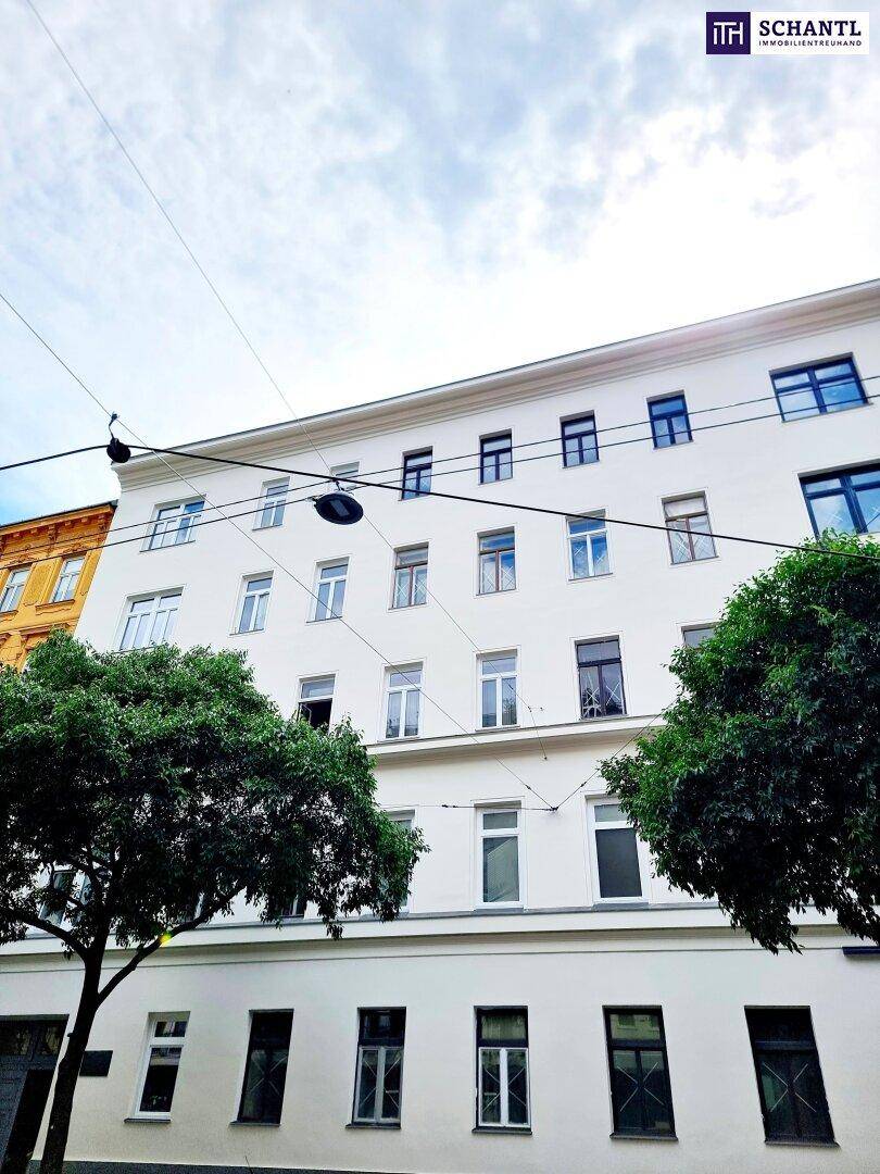 Klassische Fassade eines Wohngebäudes mit Bäumen an einer städtischen Straße.