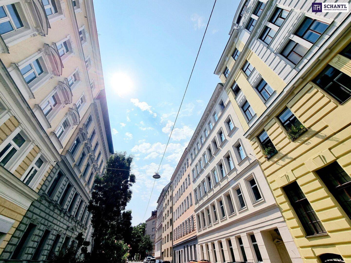 Blick auf eine belebte Stadtstraße mit historischen Gebäuden und blauem Himmel.