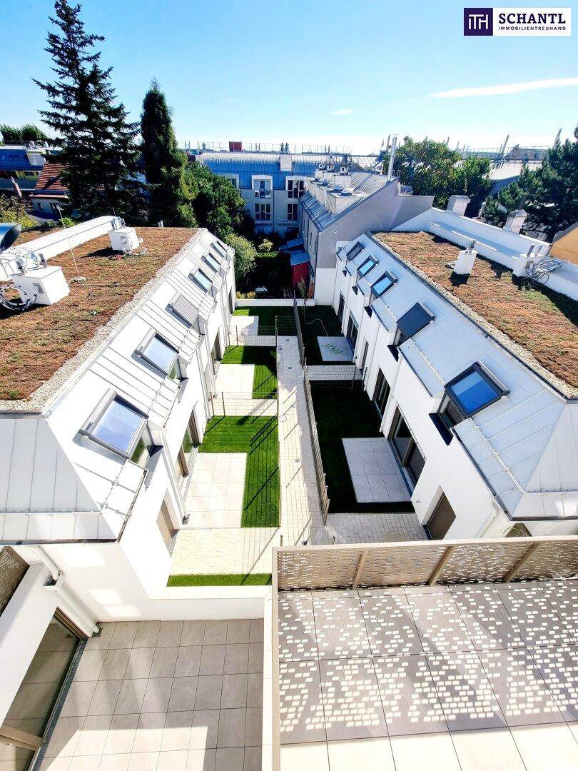 Vogelperspektive auf einen modernen Wohnkomplex mit begrünten Dächern und Innenhof.