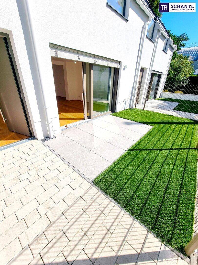 Sonniger Terrassenbereich mit Kunstrasen und Zugang zu den Wohnräumen eines modernen Hauses.
