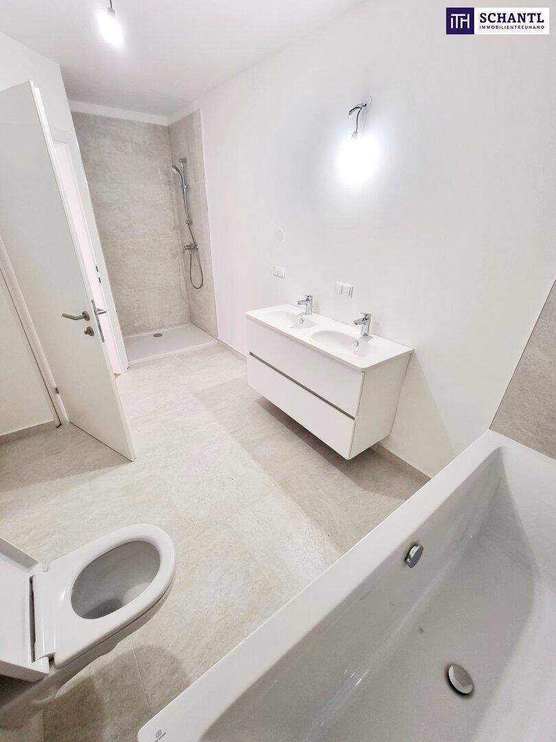 Geräumiges Badezimmer mit begehbarer Dusche, Doppelwaschbecken und modernen hellgrauen Fliesen.