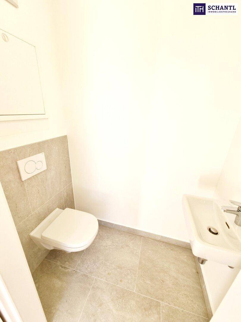 Modernes Gäste-WC mit wandhängender Toilette, kleinem Waschbecken und Fliesenboden.