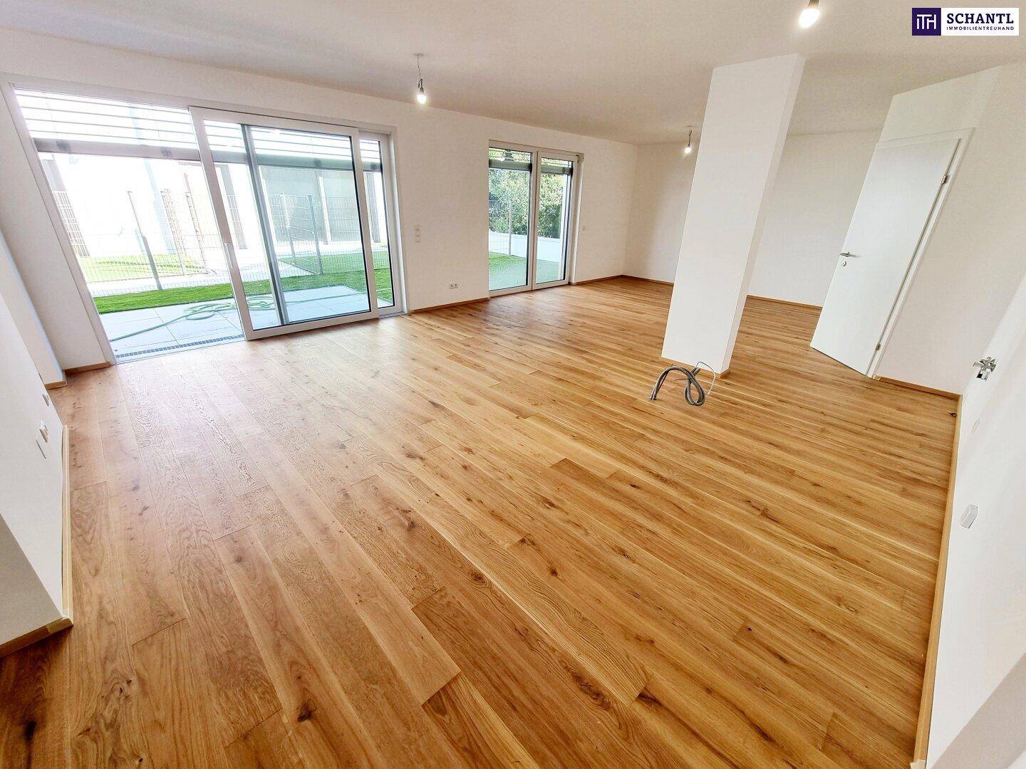 Offener Wohnbereich mit Zugang zum Garten durch große Schiebetüren und neuem Holzfußboden.