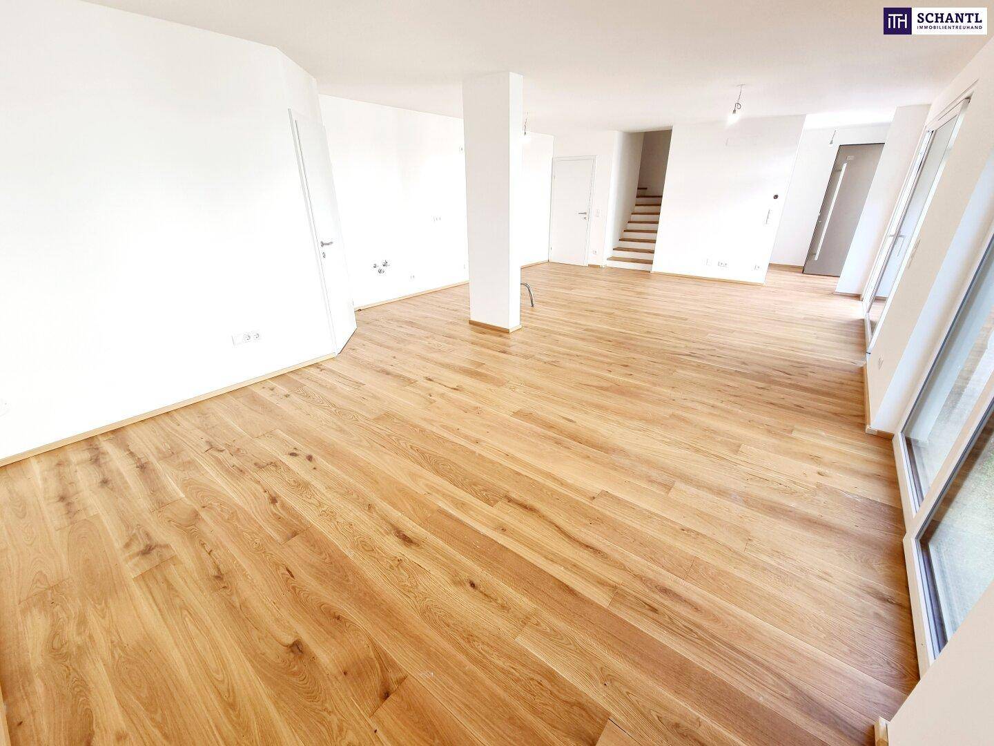 Heller Wohnbereich mit Holzparkett und Treppenzugang, bereit für individuelle Gestaltung.