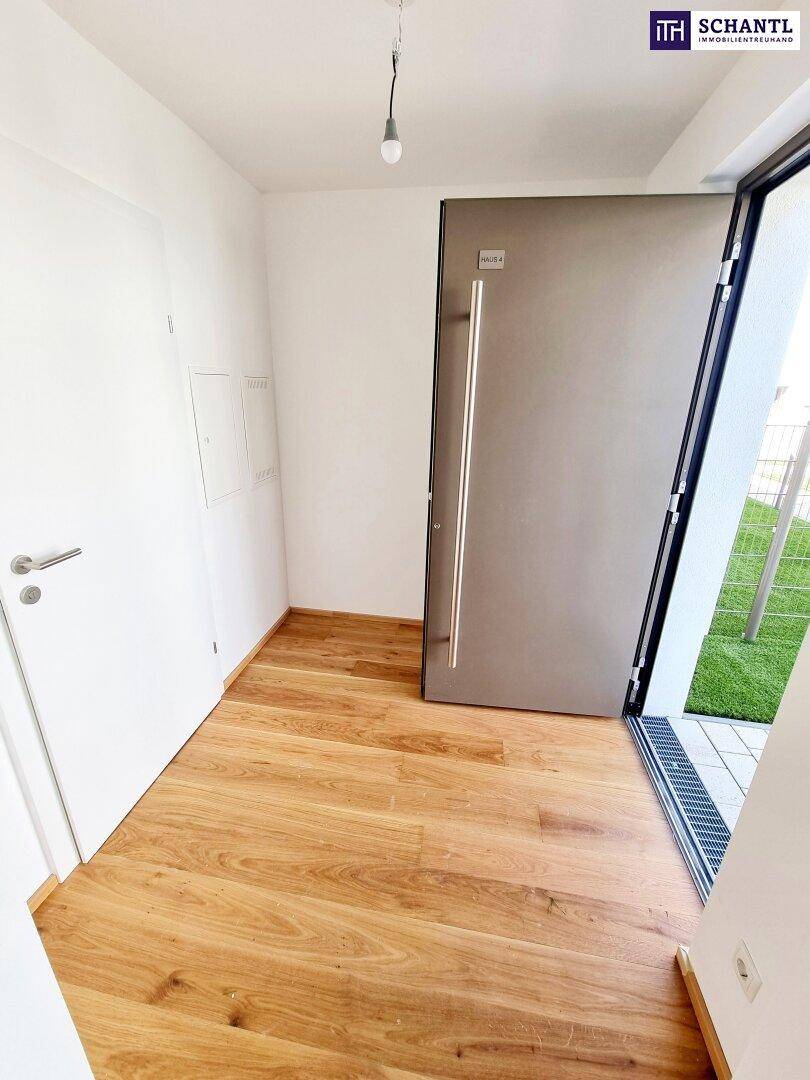 Heller Eingangsbereich mit moderner Haustür, hochwertigem Holzboden und weißen Wänden.