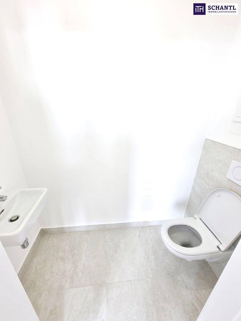 Modernes Gäste-WC mit Wand-WC, kleinem Waschbecken und hellen Fliesen.