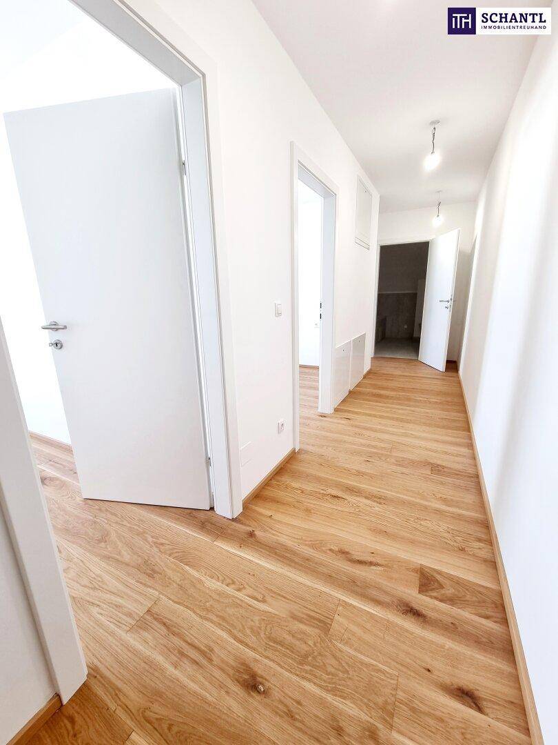 Heller Flur mit mehreren Türen und durchgehendem Parkettboden in einem Neubau.