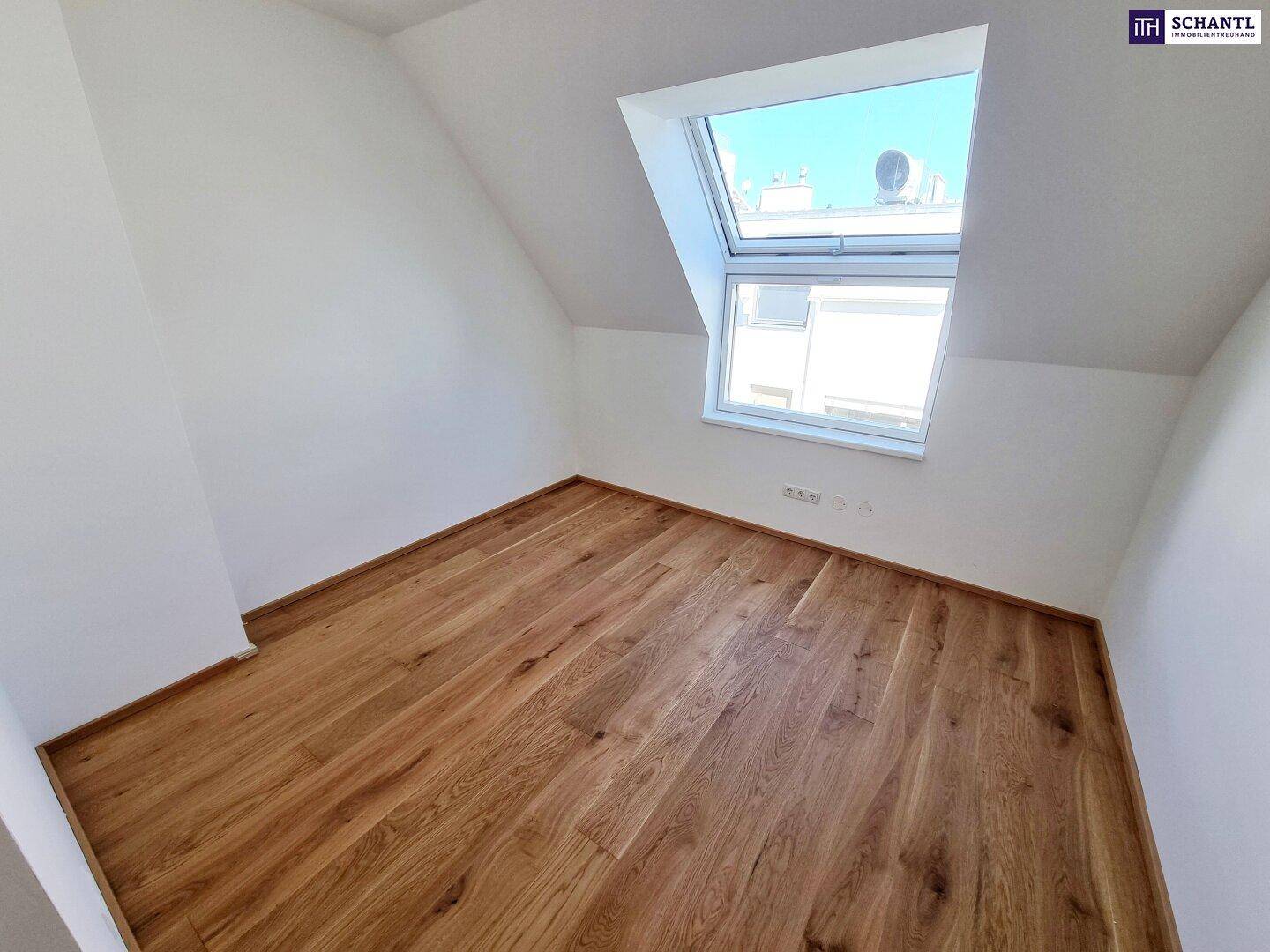 Helles Schlafzimmer im Dachgeschoss mit schrägen Wänden, Parkettboden und Dachfenster.