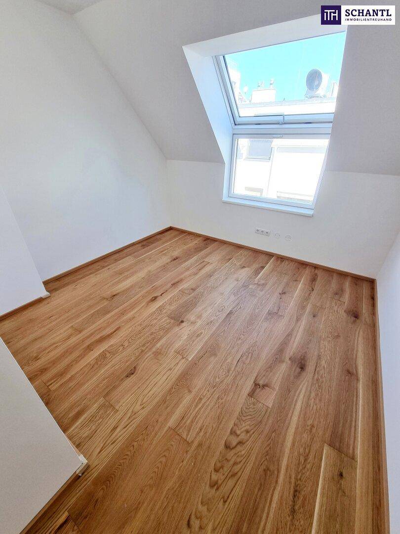 Dachgeschosszimmer mit Parkettboden und großem Dachfenster, das viel Tageslicht hereinlässt.