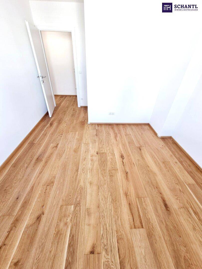 Leerer Raum mit Parkettboden und weiß gestrichenen Wänden, bereit zur Einrichtung.