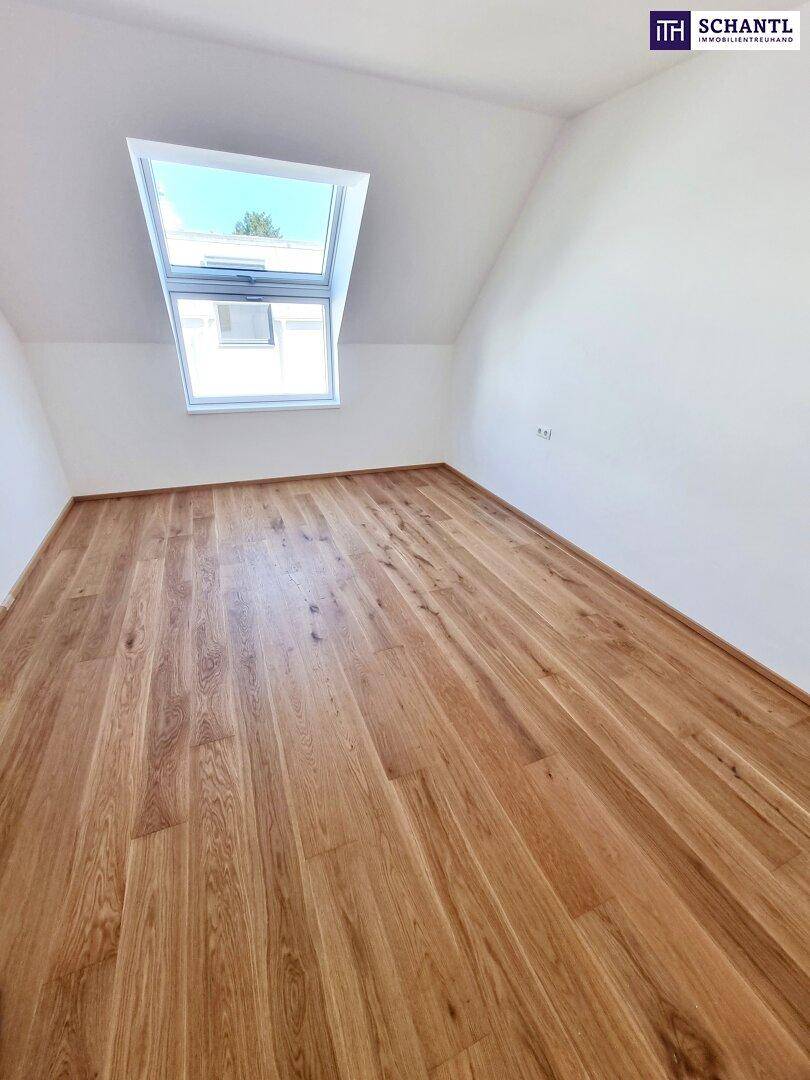 Geräumiges Dachgeschosszimmer mit Parkettboden und einem großen Dachfenster.