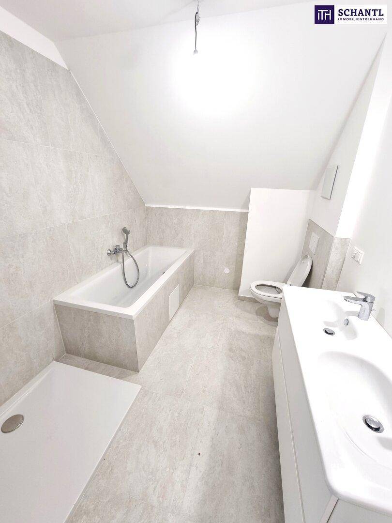 Modernes Badezimmer im Dachgeschoss mit Badewanne, Dusche, Waschbecken und hellen Fliesen.
