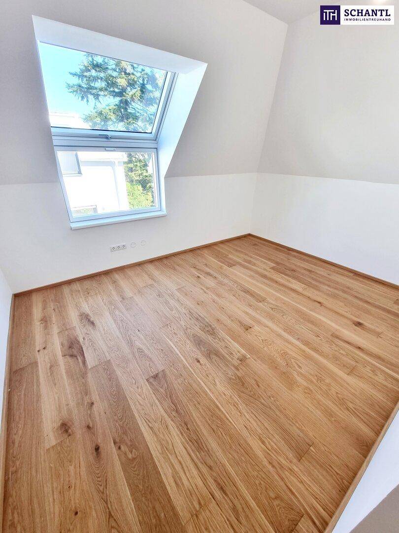 Helles Zimmer im Dachgeschoss mit Holzboden, weißen Wänden und Dachfenster.
