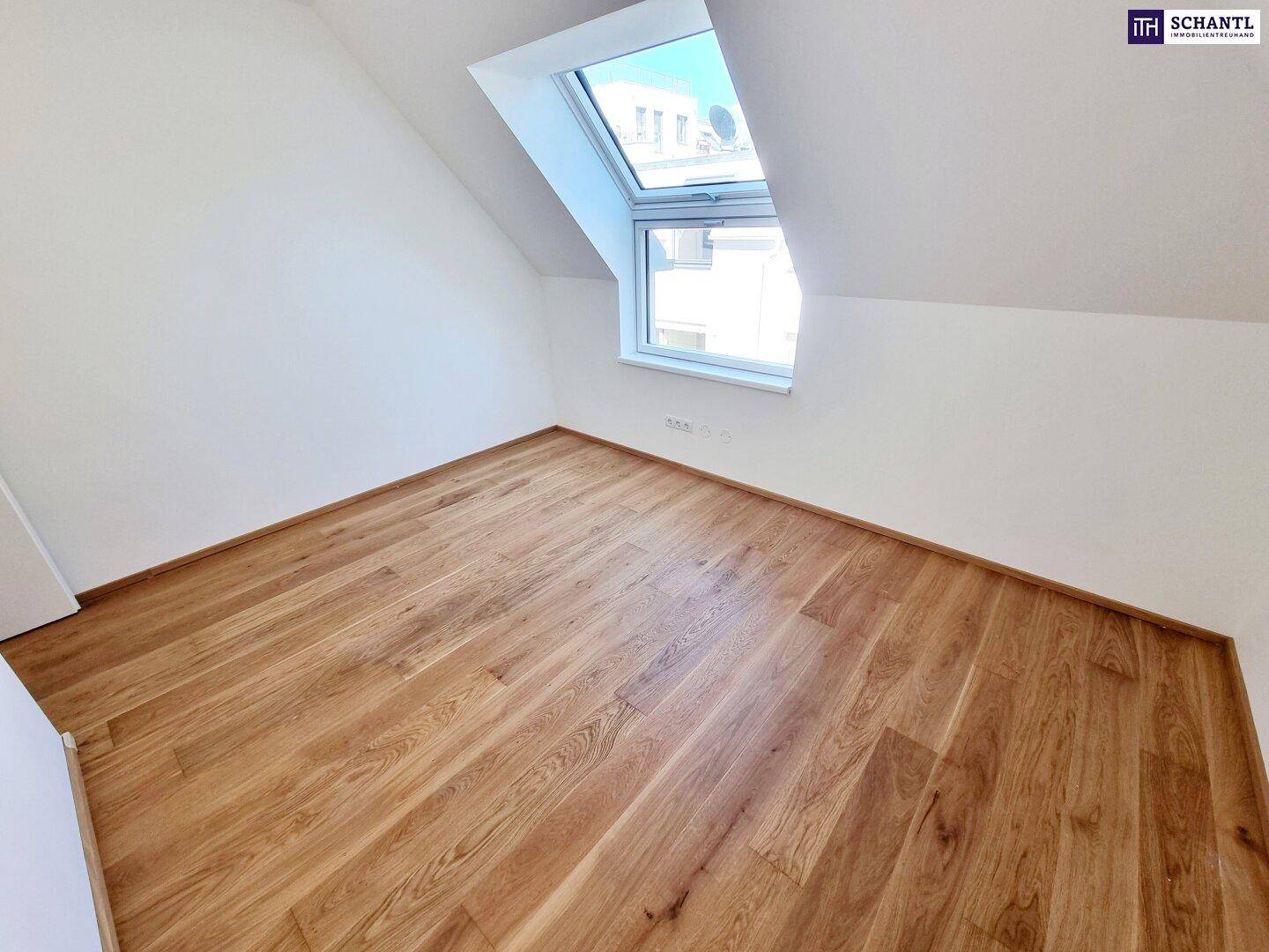 Lichtdurchflutetes Dachzimmer mit neuem Holzboden, schrägen Wänden und Ausblick.