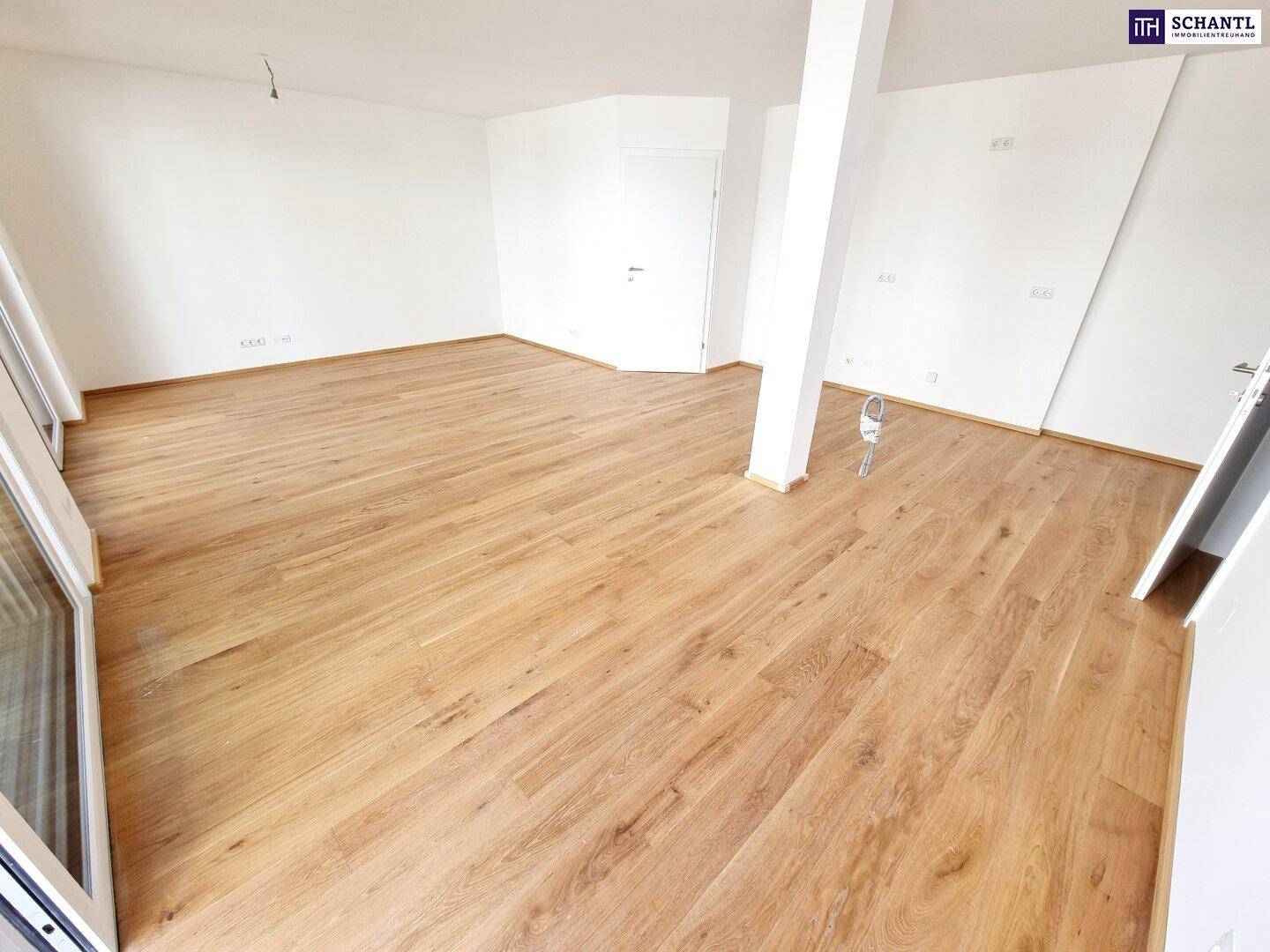 Geräumiger, heller Wohnraum mit hochwertigem Parkettboden und großen Fenstern für viel Tageslicht.