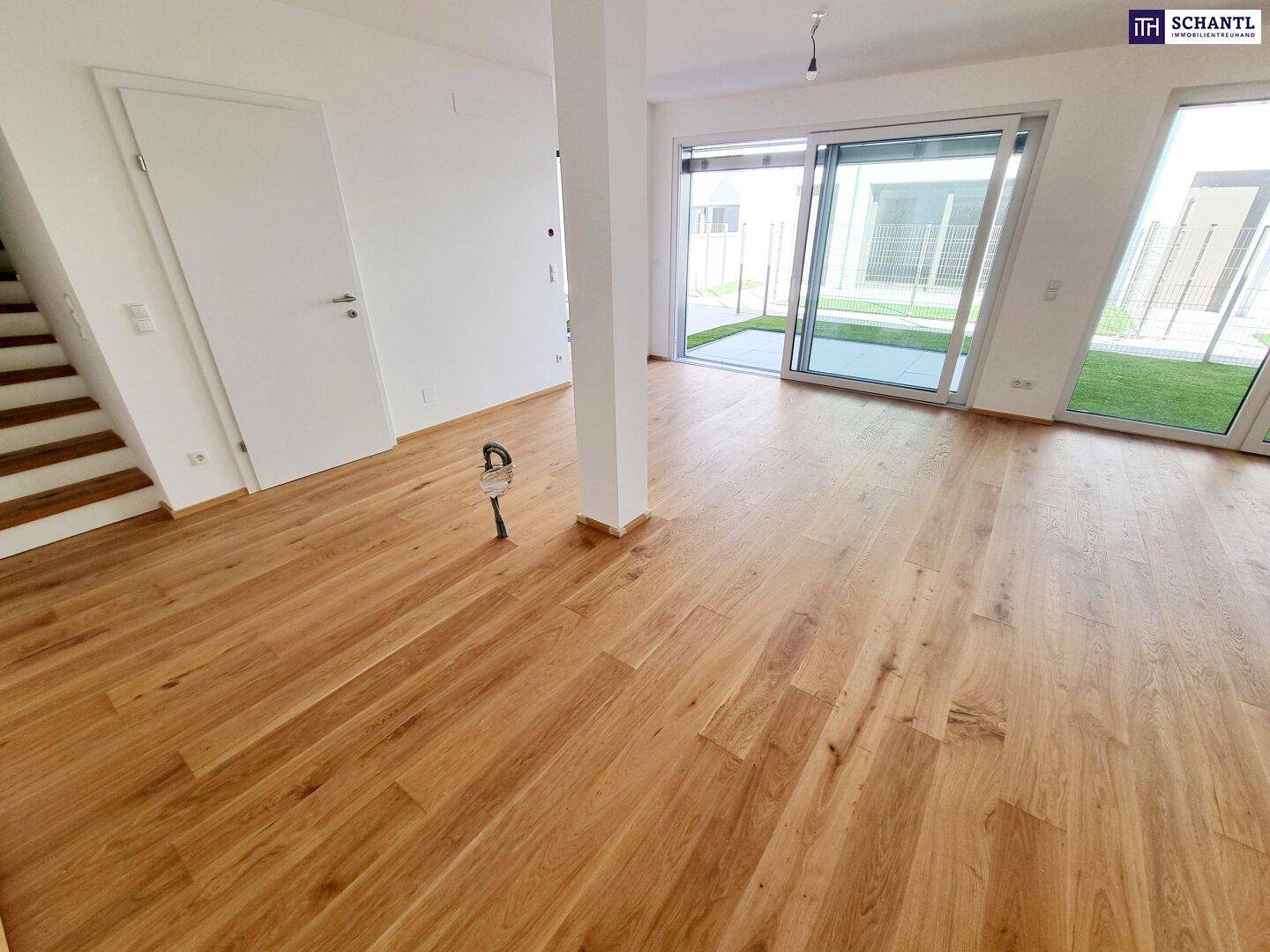 Geräumiger Wohnbereich mit hellem Parkettboden und großen Fenstern, die viel Licht hereinlassen.