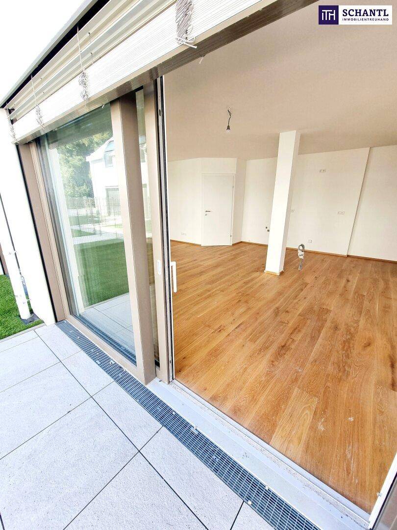 Heller Wohnraum mit Parkettboden und direktem Zugang zur Außenterrasse durch eine breite Schiebetür.
