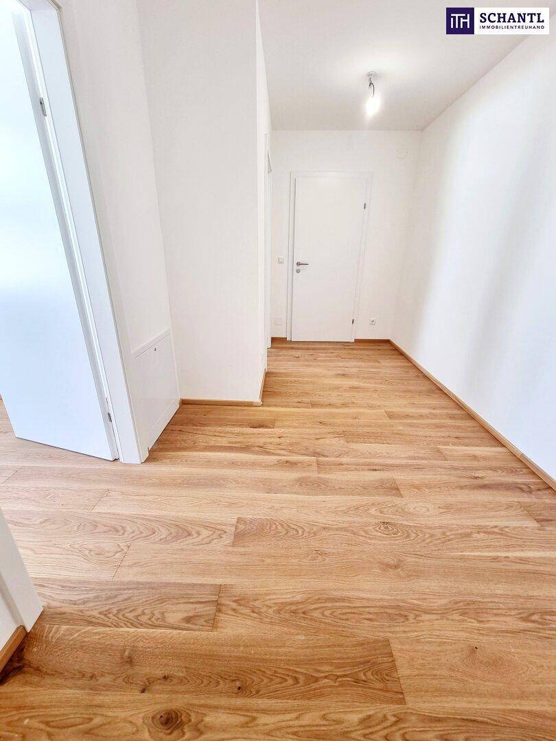 Heller Flur mit Eichenparkettboden und weißen Wänden, der zu weiteren Räumen führt.