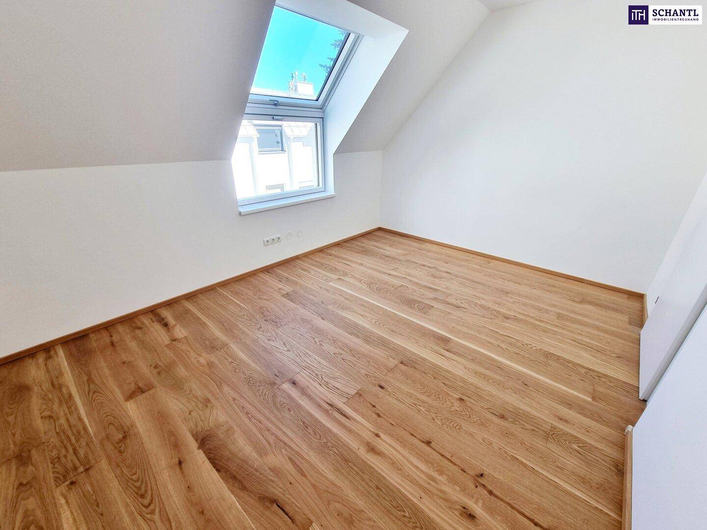 Gemütliches Zimmer im Dachgeschoss mit hellem Parkettboden und einem schrägen Dachfenster.