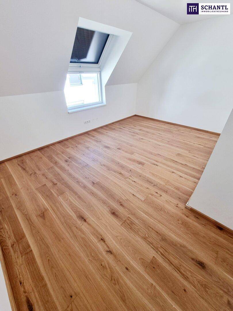 Dachgeschosszimmer mit Parkettboden, weißen Wänden und einem großen Dachfenster für viel Tageslicht.